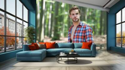 Handsome guy with unshaven face hair wear open plaid shirt in summer nature, casual Wall mural