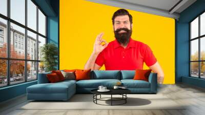 happy hipster male with beard showing ok gesture on yellow background, hairstyle Wall mural