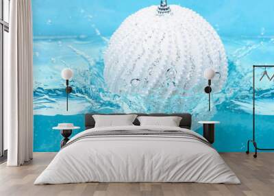 Holidays and vacation concept. Christmas decoration or toy for Christmas tree swim in pool. Festive decoration for Christmas tree, white ball dropped into water with splashes, blue background Wall mural