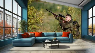 Hunting and trapping seasons. Bearded serious hunter spend leisure hunting. Hunter hold rifle. Man wear camouflage clothes nature background. Hunting permit. Hunting is brutal masculine hobby Wall mural