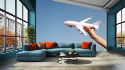 Plane in female hand clear blue sky background copy space. Travel and vacation. Book tickets now. Toy white plane fly vacation destinations. Travel comfortable premium class airlines. Discover world Wall mural