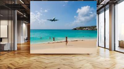 Plane land over people on beach of philipsburg, sint maarten. Jet flight low fly over blue sea. Airplane in cloudy blue sky. Beach vacation at Caribbean. Wanderlust, travel and trip Wall mural