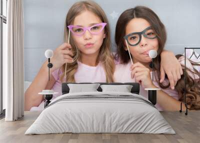 Playful mood. Girls children posing with grimaces photo booth props. Pajamas party concept. Girls friends having fun pajamas party. Friends cute and cheerful posing with eyeglasses accessories Wall mural