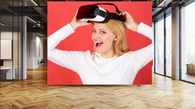 The woman with glasses of virtual reality. Person with virtual reality helmet isolated on red background. Amazed young woman touching the air during the VR experience. Wearable tech business. Wall mural