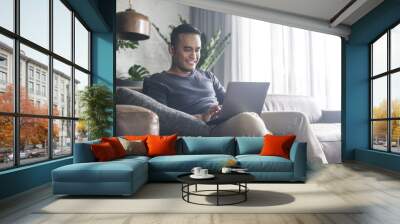 asian man looking at the computer at home. Wall mural