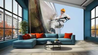 Industrial climber washing big barrel with water pressure. Risky job. Wall mural