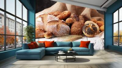 Assortment of baked bread and bread rolls on wooden table background. Wall mural