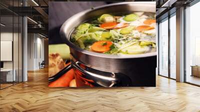 Broth with carrots, onions various fresh vegetables in a pot - colorful fresh clear spring soup. Rural kitchen scenery vegetarian broth Wall mural