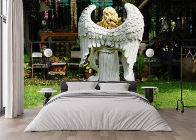 A white-winged angel statue is standing back in the park. Wall mural