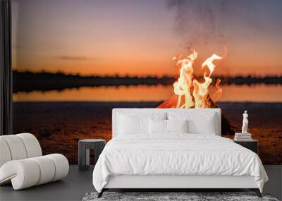 Small campfire with gentle flames beside a lake during a glowing sunset. Western Australia, Australia. Wall mural