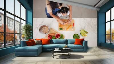 Cooking, vegetables and mom with child in kitchen cutting, peeling and prepare food. Child development, helping hands and aerial view of mother teaching girl to cook, chef skills and bond together Wall mural