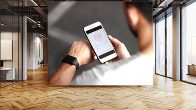 Fitness, app and man with phone, smart watch and workout schedule online at gym and sports training. Athlete with digital application, heart rate tracker and tech for exercise and health on cellphone Wall mural