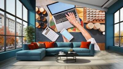 Hands, laptop and honey with a retail woman checking her phone while working at a desk in her store. Computer, ecommerce and email with a female employee typing a text message at work in her startup Wall mural