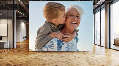 Kiss, child and grandmother in a park with love, care and freedom for happiness in retirement. Senior, smile and portrait of a woman with hug from a kid and kissing in nature or park with piggyback Wall mural