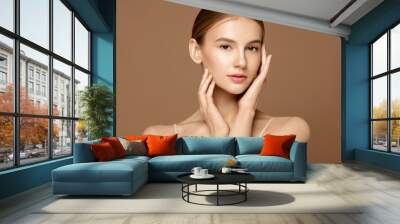 Beauty treatment portrait. Beautiful young woman with perfect skin posing against beige background. Wall mural