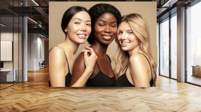 Beauty. Multi Ethnic Group of Womans with diffrent types of skin  together and looking on camera. Diverse ethnicity women - Caucasian, African and Asian posing and smiling against beige background. Wall mural