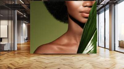 Organic skin care. Beauty portrait of young beautiful african american woman posing with exotic green leaf Wall mural