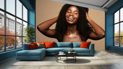 Overjoyed. Beauty fashion portrait of happy young beautiful african american woman with volume,curly hair against beige background Wall mural