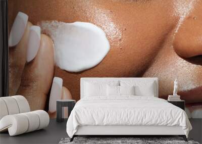 Skin care beauty portrait. Cream smear. Close up portrait of african ametrican woman is applying a skin care cosmetic on her face. Wall mural