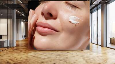 Skincare daily treatment. Beauty close up portrait of young woman with a healthy skin is applying a facial care product. Cream smear. Wall mural