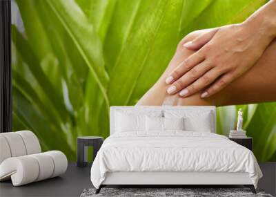 skincare. bodycare. human body part. woman applying cream or scrub on her leg against tropical green Wall mural