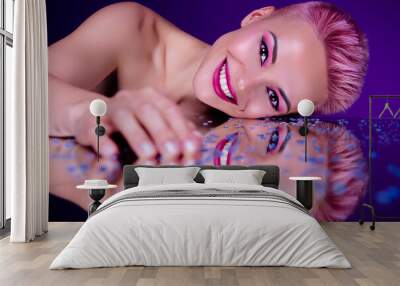 Futuristic vivid portrait of young woman model lying naked on glossy mirror covered sparkling drops cosmetics promo Wall mural