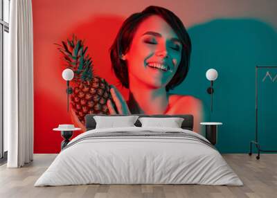 Photo of cheerful positive inspired funny woman hold exotic ananas fruit isolated red neon light color background Wall mural