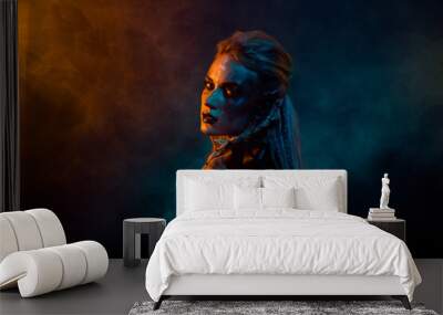 Profile photo of terrifying valkyrie pagan woman scary glance orange blue color lights isolated on dark background Wall mural