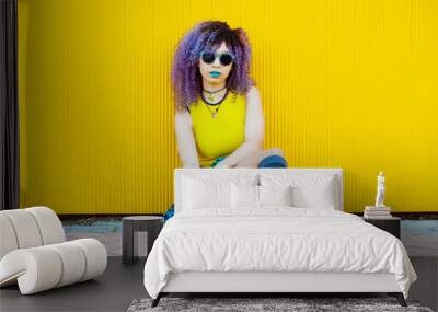 Millennial woman with urban casual style isolated on yellow background. Hair dyed with psychedelic bright colors concept. Full body of cool woman with sunglasses outdoors at summer season. Wall mural