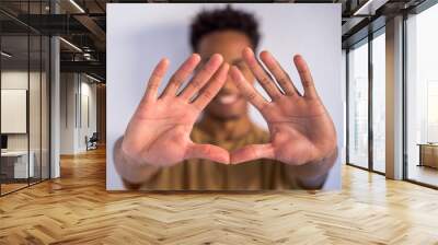 Unrecognizable african american man doing a triangle sign shape with the hands. Stop racism and embrace different ethnics. Afro culture lifestyle. Detail of wide open hands together in the front. Wall mural