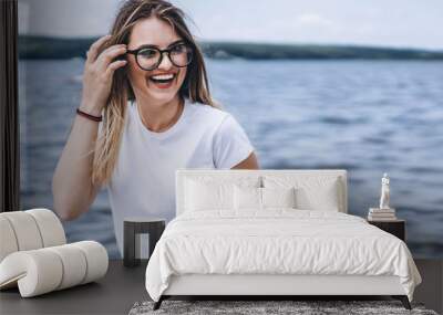 Portrait of a beautiful young woman in stylish glasses. Girl in white tshirt posing on the background of the lake landscape Wall mural