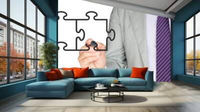 Businemman in a grey suit drawing two jigsaw pieces Wall mural