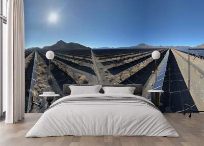 A large solar farm in a desert, with rows of panels stretching to the horizon under a clear blue sky Wall mural