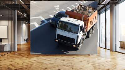 The dump truck truck carries construction waste, pieces of brick, concrete, earth, sand, pieces of wood. A truck is driving along the city ring road. Wall mural