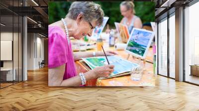 Senior woman smiling while drawing with the group. Wall mural