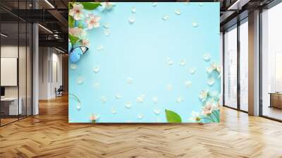 Beautiful spring nature background with butterfly, lovely blossom, petal a on turquoise blue background , top view, frame. Springtime concept. Wall mural