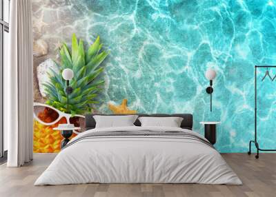 Ripe pineapple in stylish sunglasses and seashells in blue sea, relaxing. Tropical summer vacation concept Wall mural