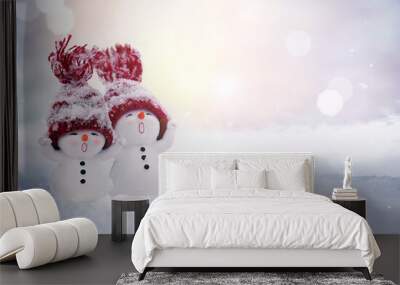 Two little snowmen in caps on snow in the winter. Background with a funny snowman. Christmas card. Wall mural