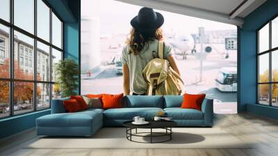 Girl in hat with backpack traveling in the airport Wall mural