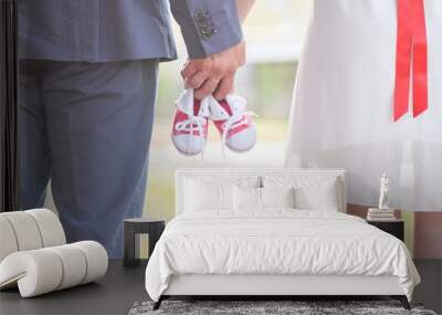 An image of adults holding baby pair of sneakers in red. Pregnancy and expectation. Wall mural