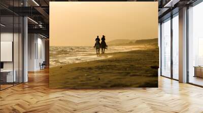 Horse rider couple at sunset beach, next to the sea Wall mural