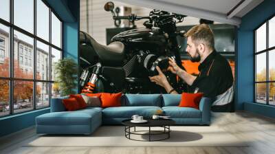 Professional mechanic change the air filter in the motorcycle. Handsome young man repairing motorcycle in repair shop. Wall mural