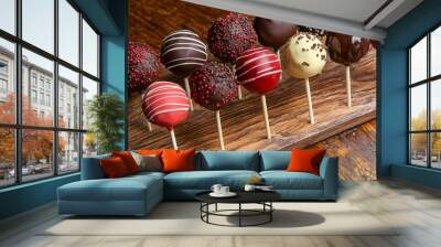 Delicious assorted cake pops on a wooden platter. Wall mural