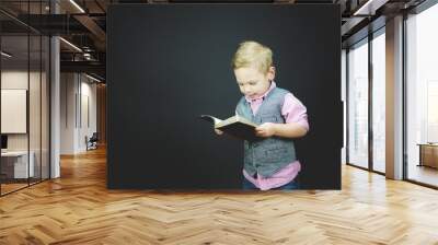 Closeup shot of a child reading a bible with a black background Wall mural