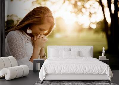 Closeup shot of a female with her eyes closed praying and a blurred background Wall mural