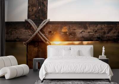 Closeup shot of a wooden cross with the sun in the blurred background Wall mural