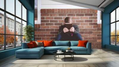 Closeup shot of a young male sitting with a book in hands Wall mural