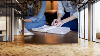 Closeup shot of females sitting and reading the bible with blurred background Wall mural