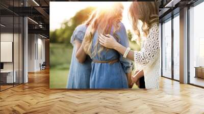 Closeup shot of females with their arms on each other while praying with a blurred background Wall mural