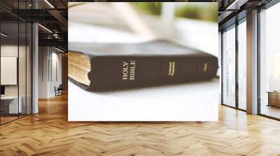 Closeup shot of the holy bible on a white surface with a blurred background Wall mural